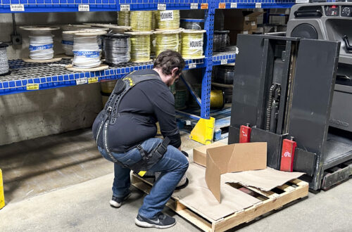 Cariste portant un exosquelette lombaire lors d'une reprise de colis en entrepôt