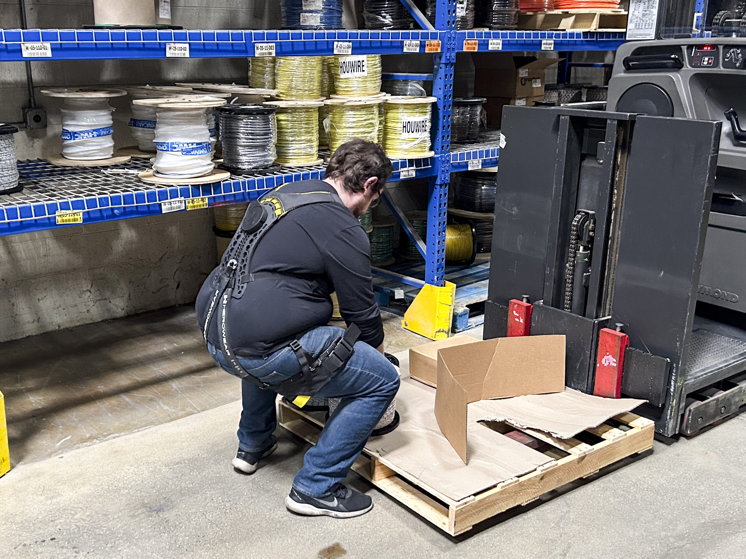 Cariste portant un exosquelette lombaire lors d'une reprise de colis en entrepôt
